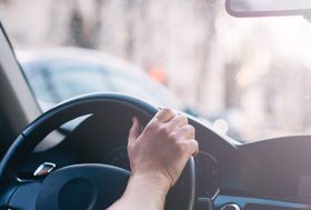 Conductor dentro de un coche con las manos en el volante.