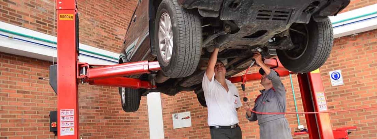 Personas mirando un coche por debajo