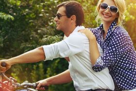 Pareja sonriente sobre una moto