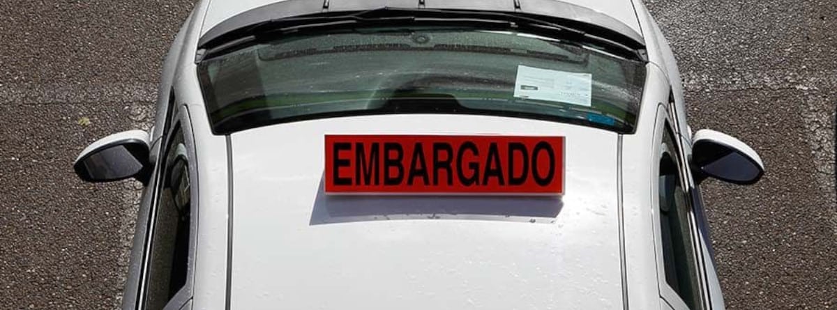 Coche blanco con cartel rojo de embargado