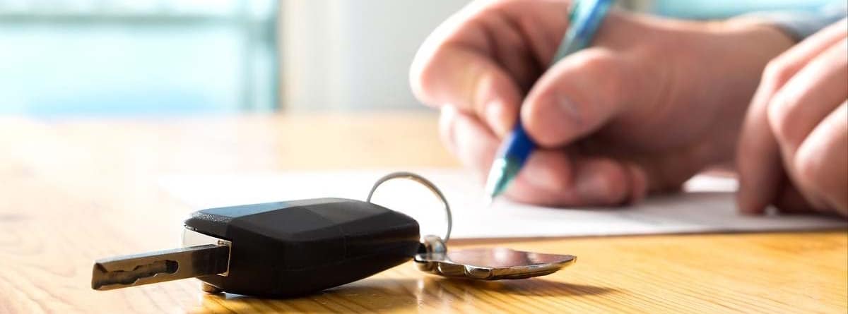 MAno escribiendo y llaves de coche en una mesa